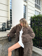 Full-length shot of a woman in a long brown faux fur coat.