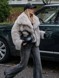 woman wearing a light grey faux fur jacket and dark wash jeans