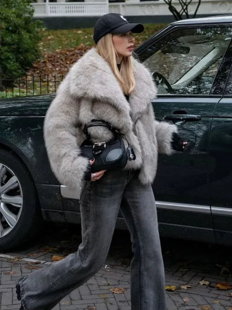 woman wearing a light grey faux fur jacket and dark wash jeans