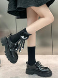 Side view of a person wearing black novelty socks with an eye applique and button details, and black platform shoes.