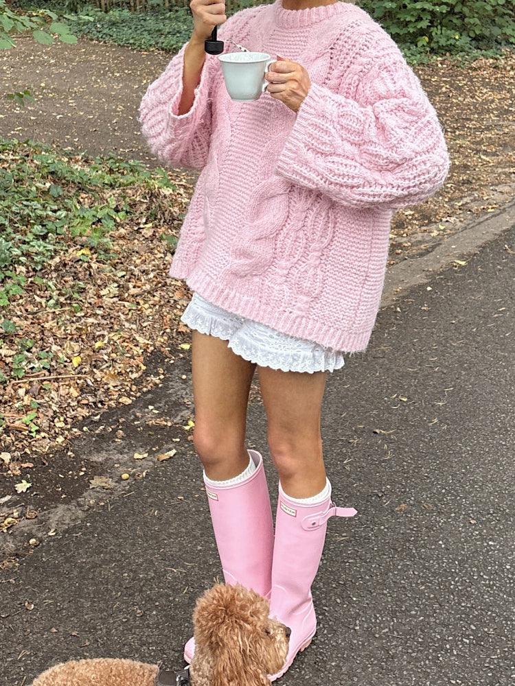 Woman holding a mug and umbrella in a pink chunky cable knit sweater