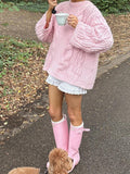 Close-up of a pink chunky cable knit sweater with intricate cable details