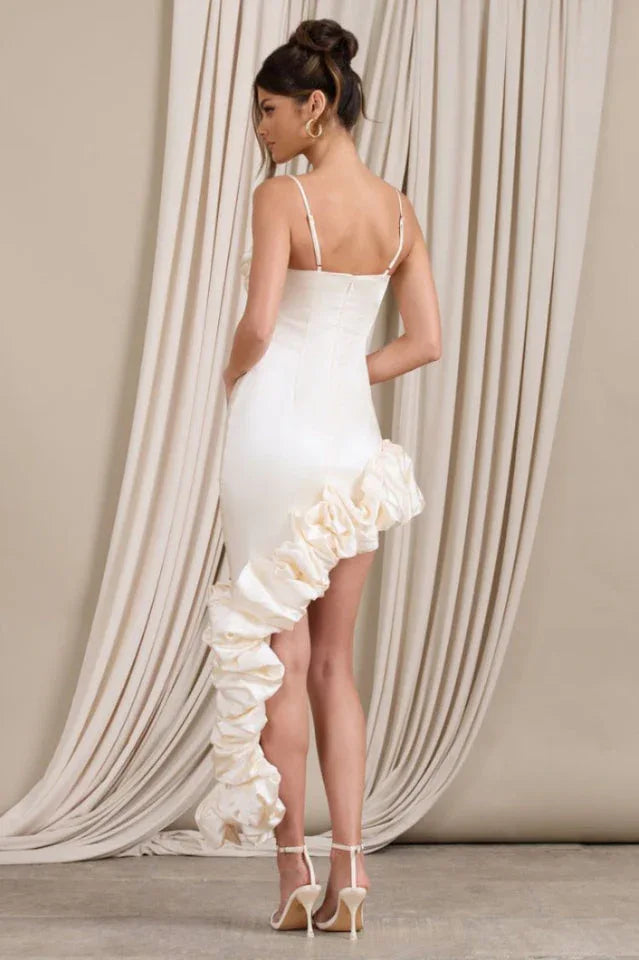 Rear view of a cream satin bodycon dress with spaghetti straps and a cascading ruffle detail on the side.