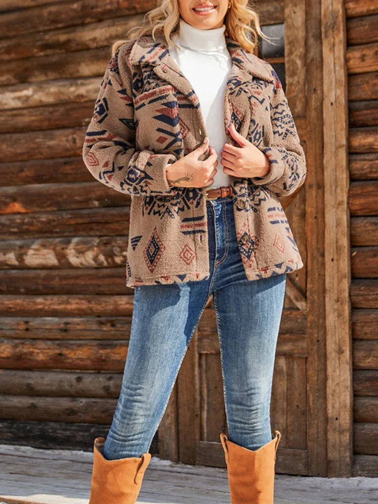 Woman wearing a brown fleece jacket with a geometric print, white turtleneck, and blue jeans.