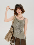 Woman wearing a green graphic print tank top with buckle shoulder straps