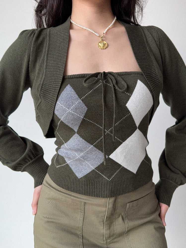 Woman wearing a dark green argyle print knit tube top with a tie front and a matching dark green knit bolero with puff sleeves.