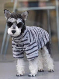 Full body shot of a dog in a grey and black striped terry cloth sweater.