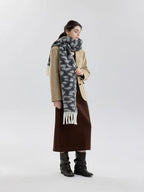 Full body shot of a woman in a beige blazer, brown skirt, and a grey and white leopard print fuzzy scarf with fringe trim.