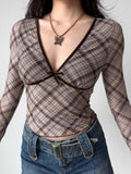 Model wearing a brown plaid long-sleeve top with a deep V-neck and velvet trim.