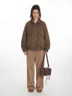 Woman wearing a brown textured bomber jacket with a collared neckline and button closure.