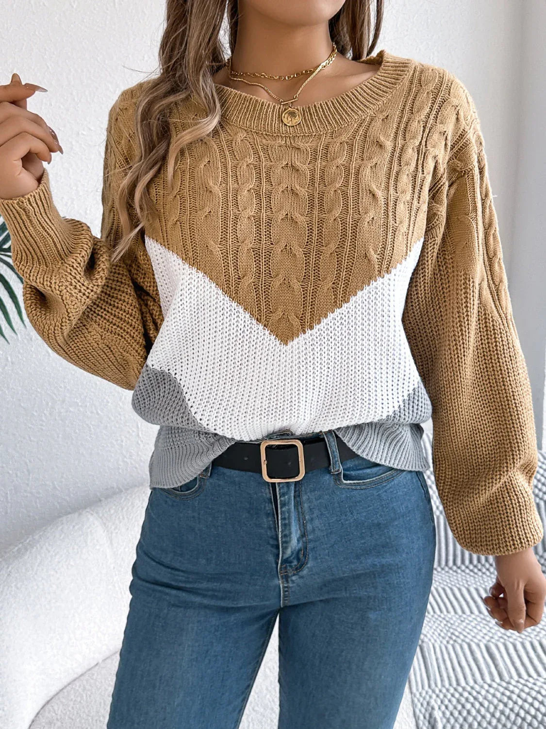 Woman wearing a tan, white, and grey chevron color block knit sweater with cable knit sleeves Main image