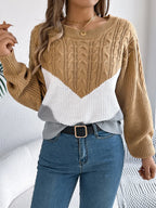 Woman wearing a tan, white, and grey chevron color block knit sweater with cable knit sleeves