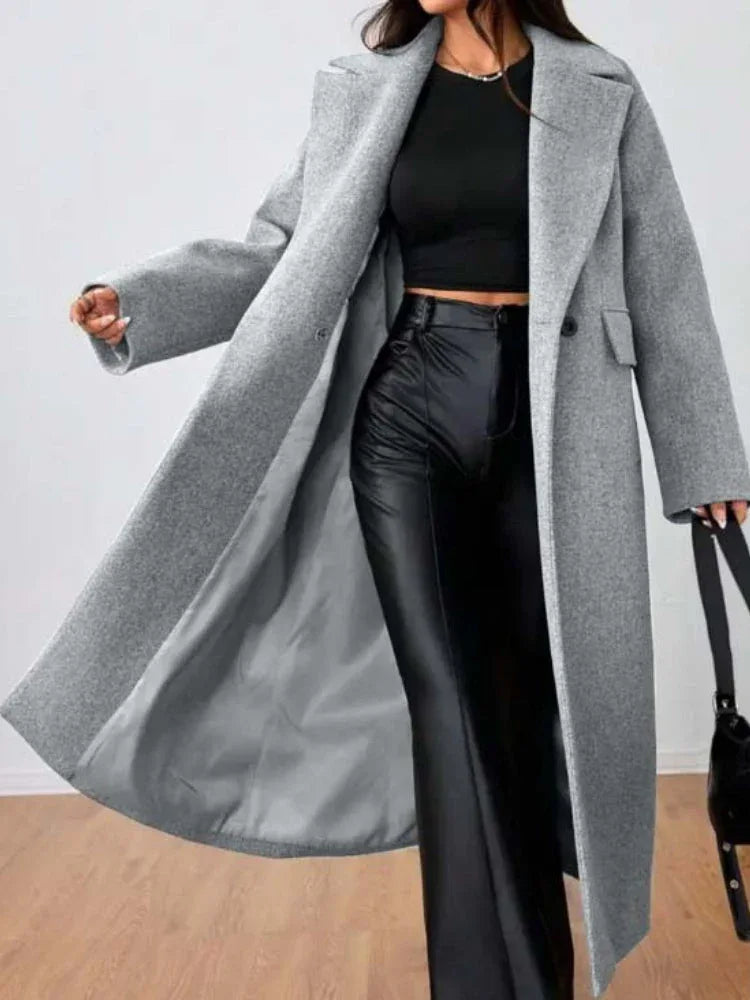 Woman in a grey longline wool blend coat, showing the open front and notched lapels.