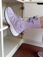 A person wearing a lavender ankle sock with a blue knitted animal appliqué, paired with a lavender sneaker.