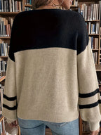 Back view of a woman wearing a black and beige color block knit sweater with striped sleeves.