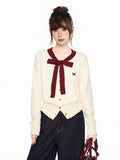 Close-up of the cream knit cardigan with burgundy trim and bow