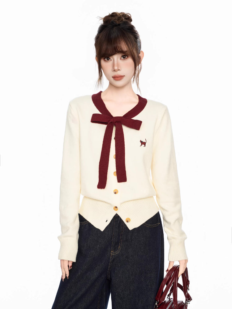 Close-up of the cream knit cardigan with burgundy trim and bow