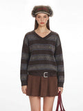 Close-up of a woman's torso showing the detail of a brown knit sweater with stripe and fair isle patterns.
