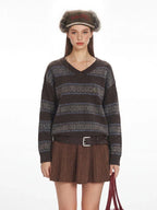 Close-up of a woman's torso showing the detail of a brown knit sweater with stripe and fair isle patterns.