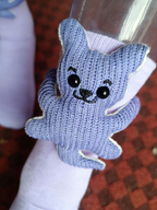 Detailed view of a blue knitted teddy bear appliqué on a lavender sock.