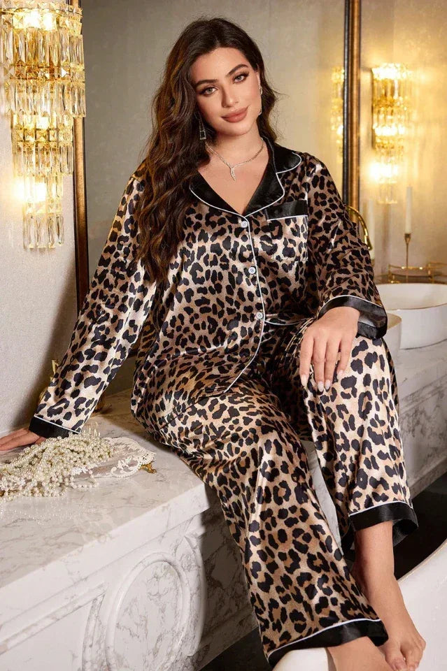Woman wearing a leopard print satin pajama set with black and white piping, sitting on a counter.