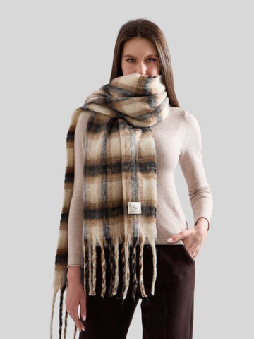 Woman wearing a cream coat and a plaid scarf with pink and brown tones