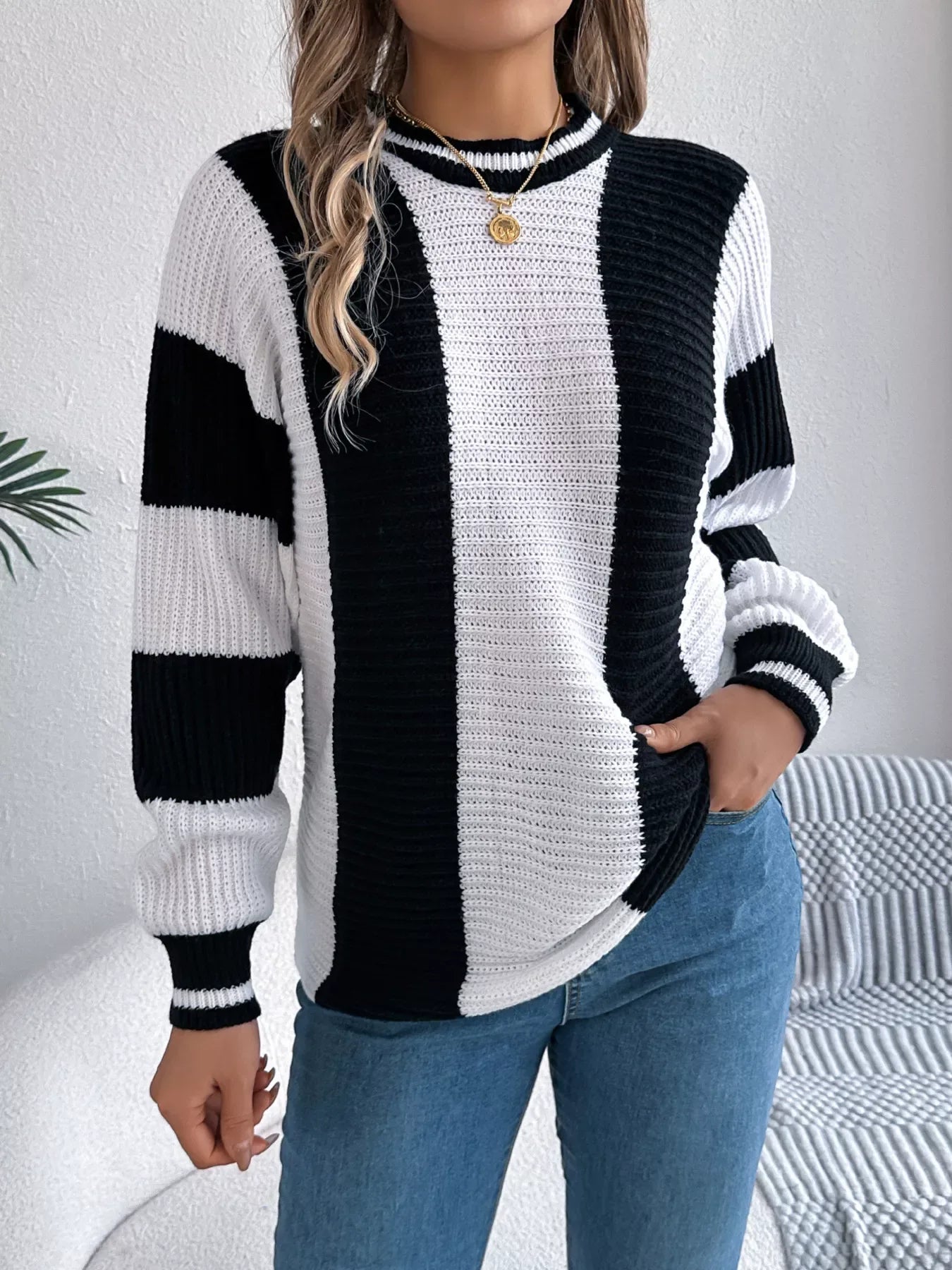 Woman wearing a black and white striped knit sweater with blue jeans.