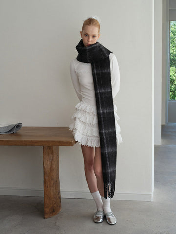 woman wearing a black and grey tartan scarf draped around her neck