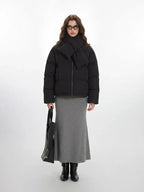 Woman wearing a black puffer jacket with a scarf and grey maxi skirt
