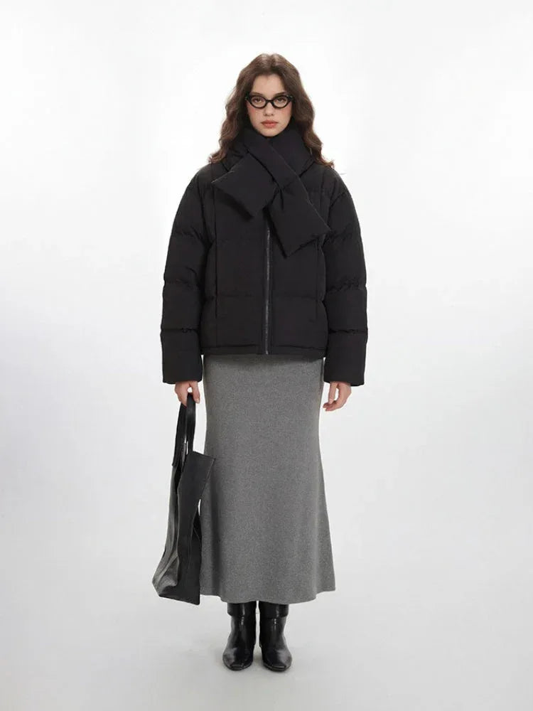 Woman wearing a black puffer jacket with a scarf and grey maxi skirt