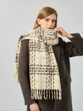 Woman adjusting a cream and brown plaid scarf with fringe.