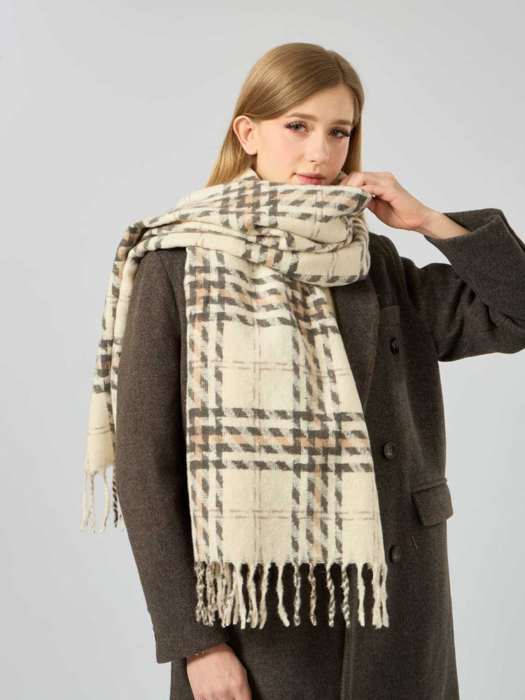 Woman adjusting a cream and brown plaid scarf with fringe.