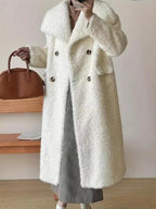 Woman wearing a long white textured fleece coat with a double-breasted closure and patch pockets.