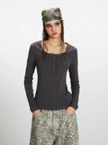 Front view of a woman wearing a dark grey long-sleeve ribbed knit top with a square neckline and buttoned placket, styled casually.