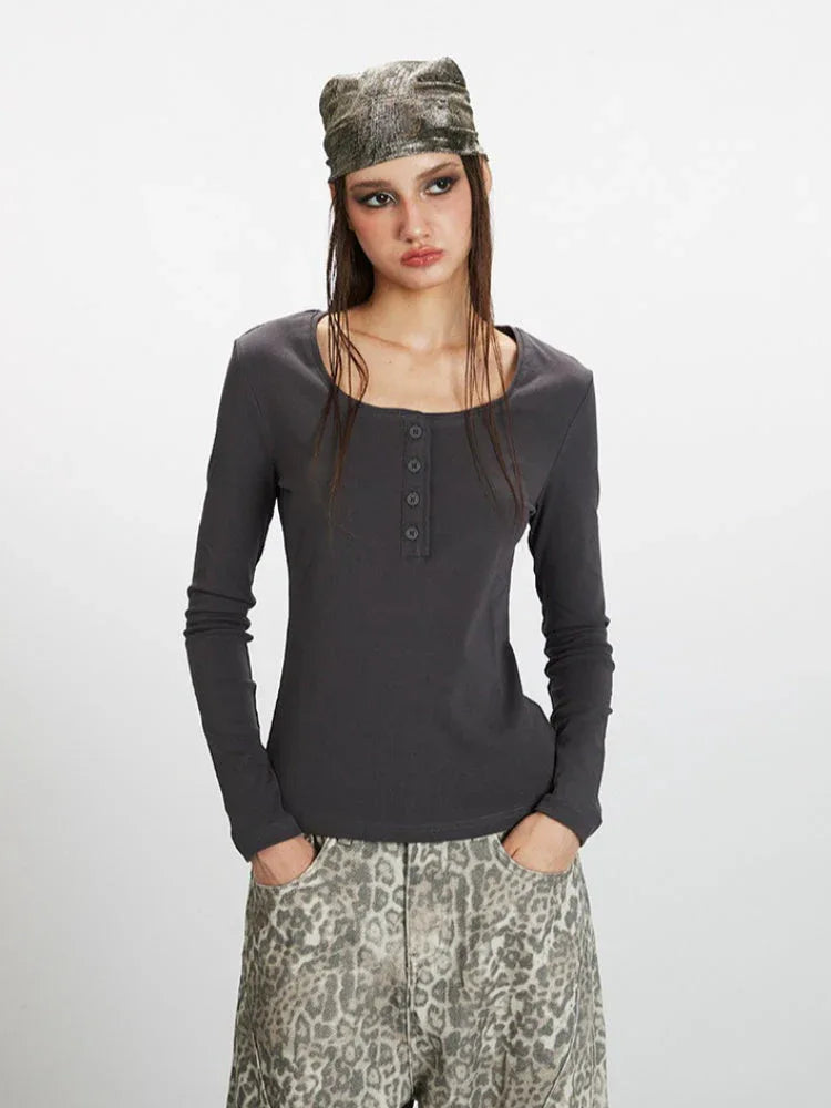 Front view of a woman wearing a dark grey long-sleeve ribbed knit top with a square neckline and buttoned placket, styled casually.