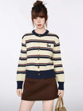 Woman wearing a cream and navy striped knit cardigan with a dachshund embroidery detail