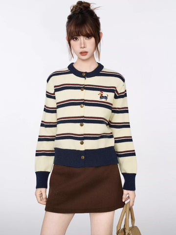 Woman wearing a cream and navy striped knit cardigan with a dachshund embroidery detail
