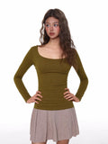 Woman wearing a fitted, long-sleeve olive green ribbed top with a scoop neckline.