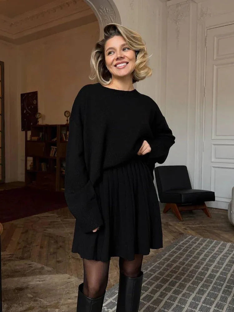 Woman wearing a black knit sweater and pleated skirt set