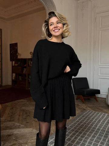 Woman wearing a black knit sweater and pleated skirt set