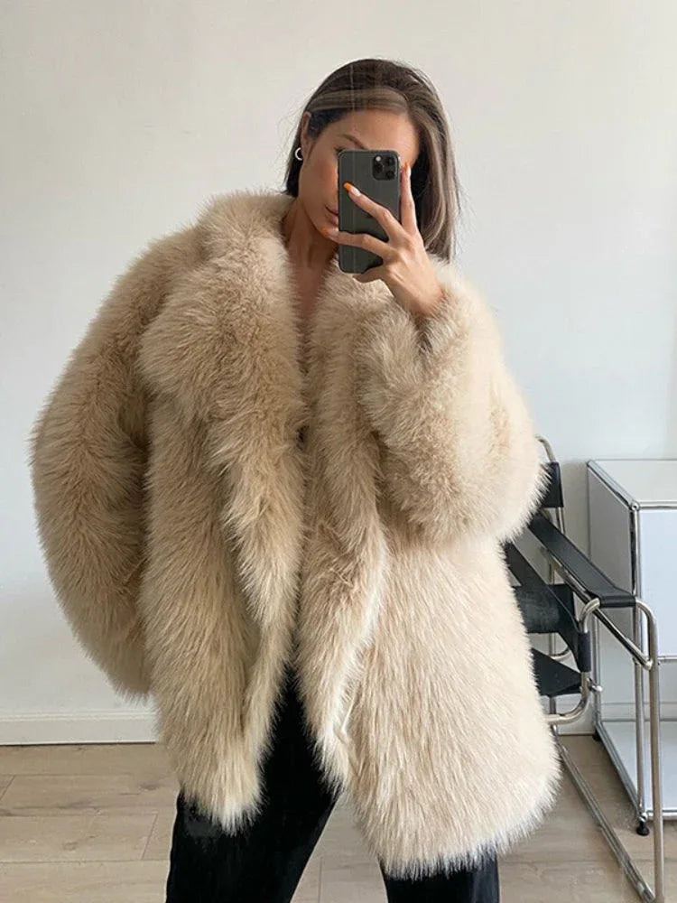 Woman wearing a brown shaggy faux fur coat and blue jeans sitting on a couch outdoors. Main image