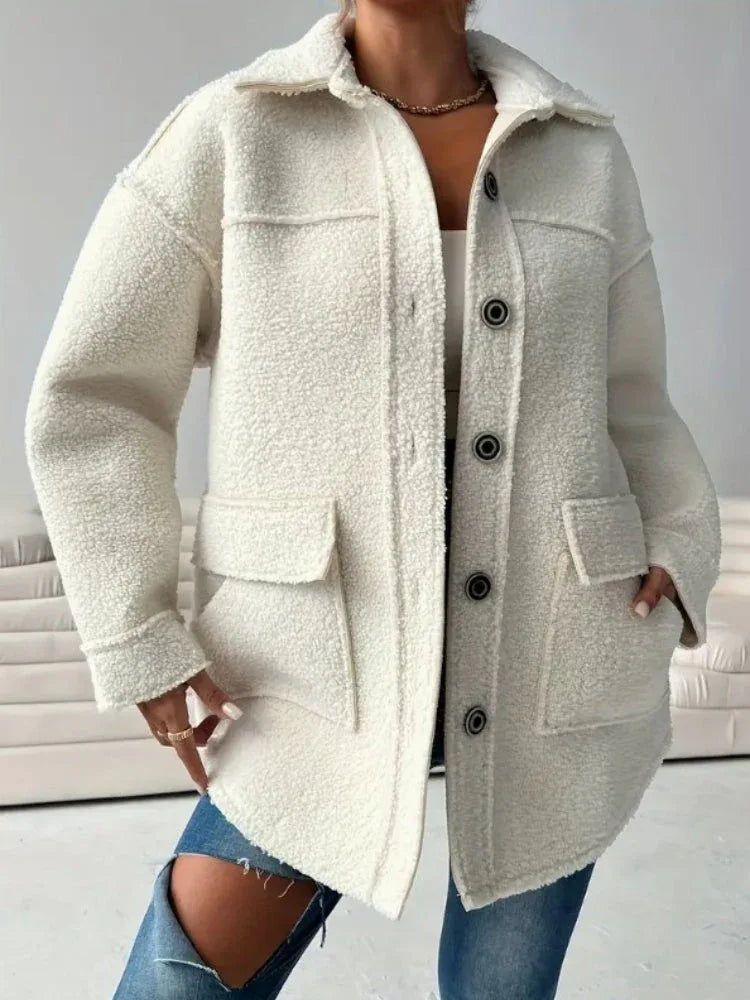 Close-up of a woman wearing a cream-colored oversized fleece jacket, highlighting the button details and textured fabric.