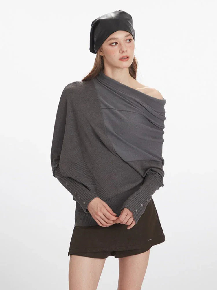 Woman showcasing the off-the-shoulder styling of a grey asymmetrical knit sweater with draped overlay.
