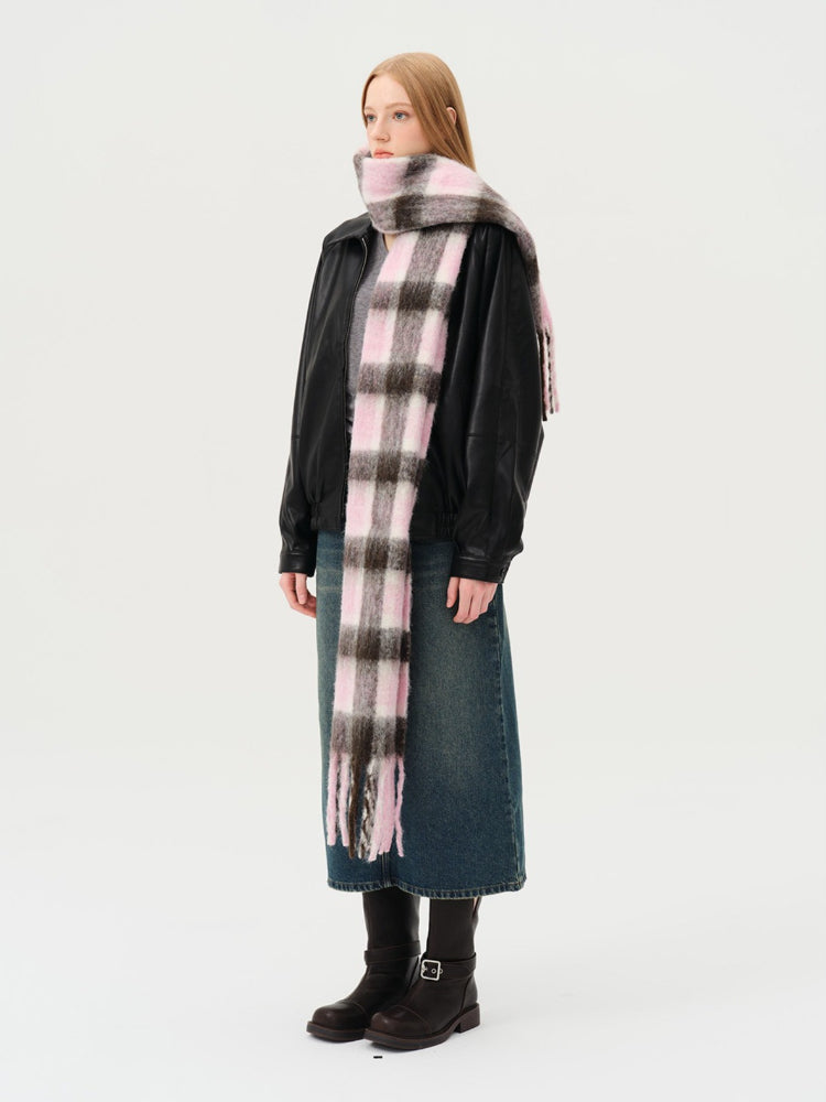 Woman wearing a black jacket and a pink and brown plaid scarf