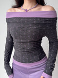 Detailed view of the off-the-shoulder neckline and print on a grey and purple long-sleeve top.