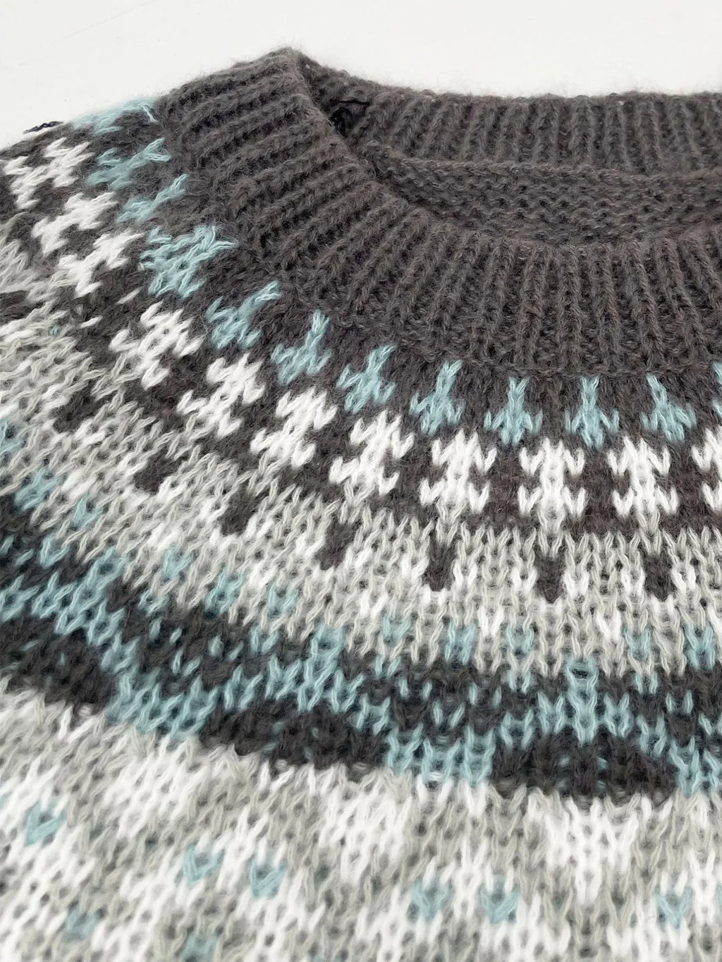 Close-up of the crew neck and Fair Isle pattern on a grey knit sweater