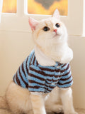 Cat wearing a blue and brown striped fleece pet jacket with a white collar.