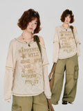 Model posing in a cream-colored long-sleeved graphic t-shirt and olive green cargo pants.