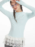 Close-up of the upper body of a woman wearing a light blue long-sleeved top with lace trim and graphic detail.