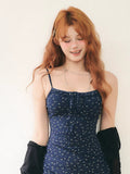 Close-up of a woman wearing a navy floral print mini dress with spaghetti straps and a tie-front detail.
